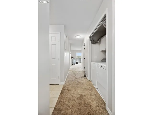 a view of a hallway with white walls and a bathroom