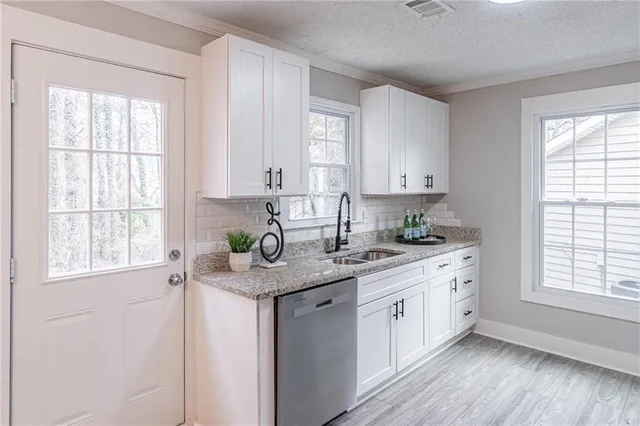 a kitchen with stainless steel appliances granite countertop a sink a stove cabinets and a window