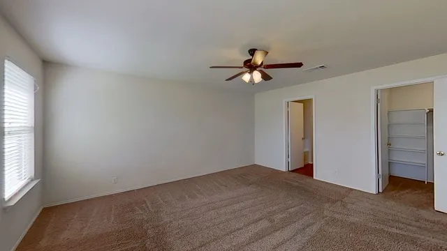 a view of empty room with window and ceiling fan