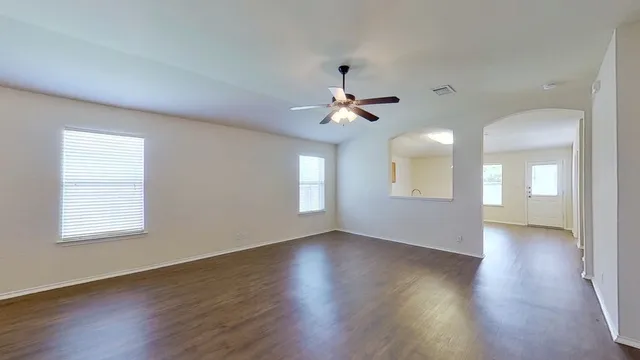 a view of an empty room with a window and wooden floor