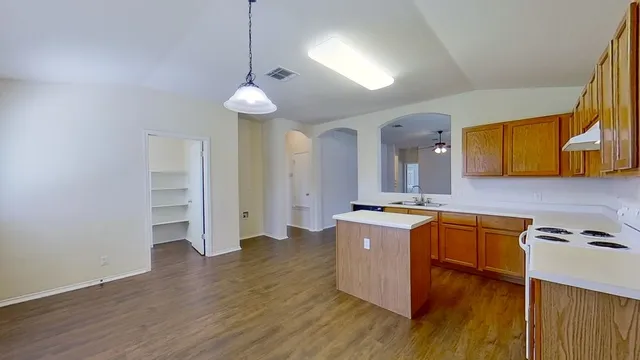 a kitchen with stainless steel appliances granite countertop a sink cabinets and wooden floor