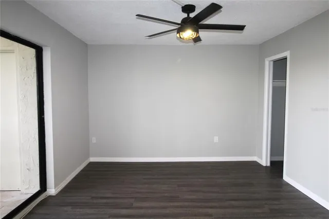 an empty room with wooden floor and ceiling fan