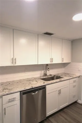a kitchen with a sink dishwasher and cabinets with wooden floor