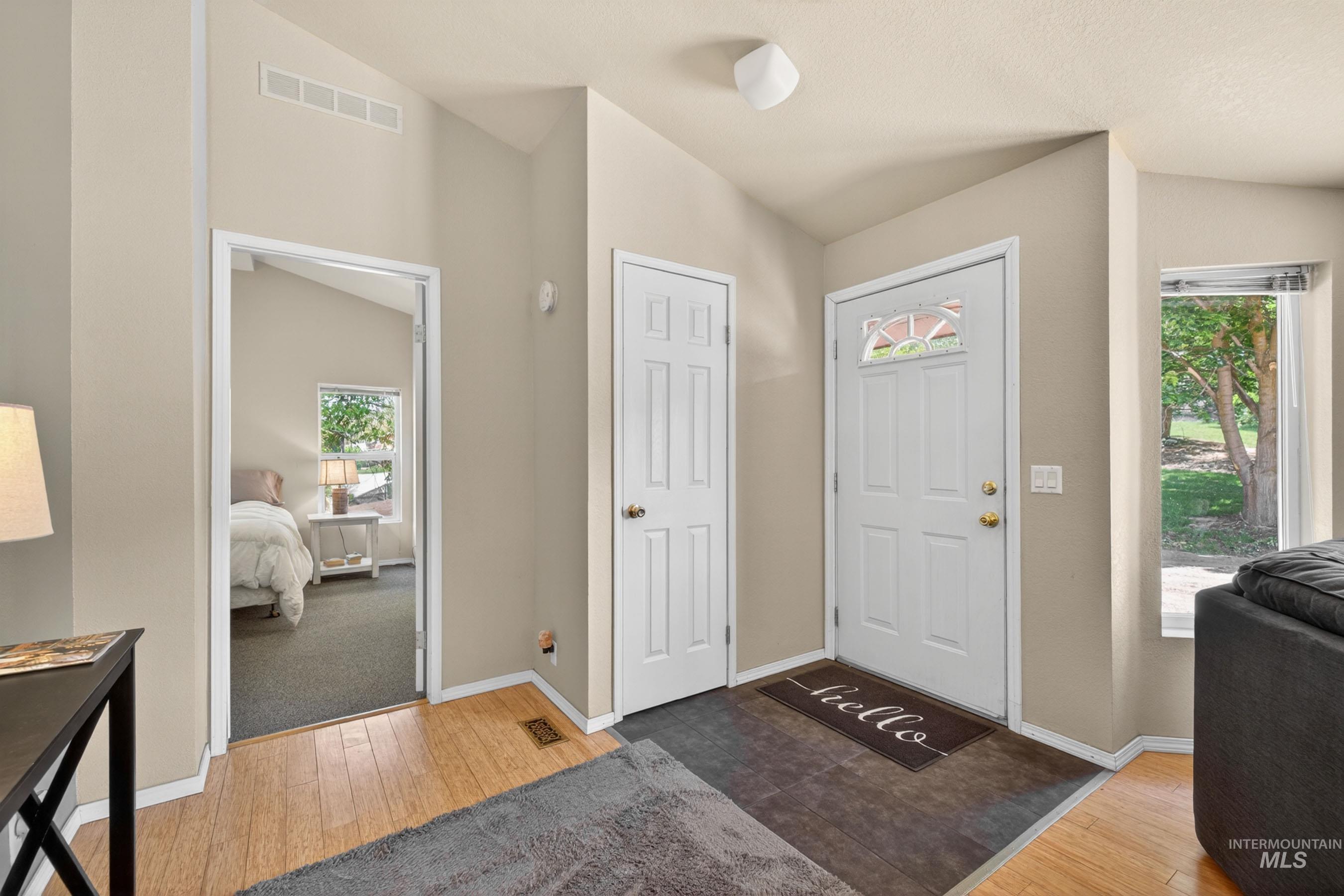 151 Cow Creek Road Lucile, ID 83542 - Photo 6 of 50 Entryway featuring light wood-finish flooring, a white paneled door with decorative glass, and vaulted ceilings
