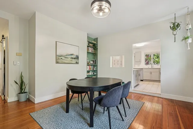 a dining room with wooden floor a chandelier a wooden table and chairs