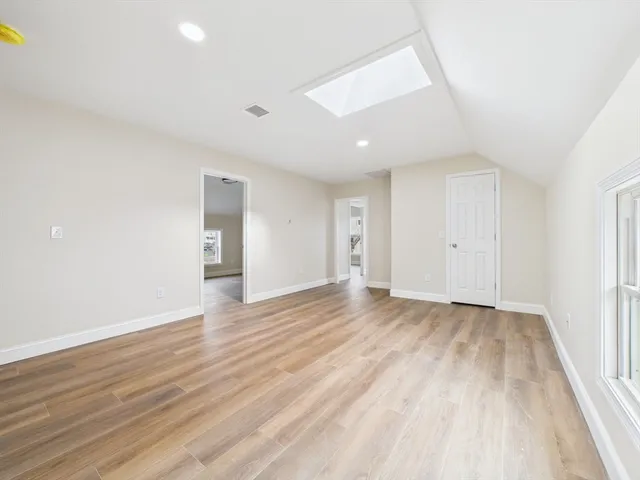an empty room with wooden floor and natural light
