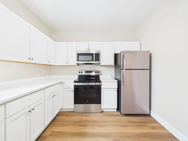 a kitchen with a refrigerator stove and white cabinets
