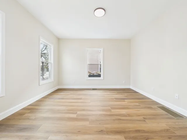 a view of an empty room with window and wooden floor
