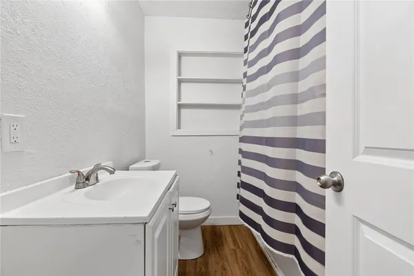 a bathroom with a sink a toilet a mirror and shower curtain