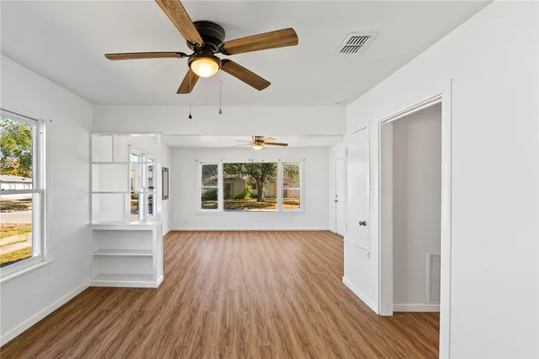 a view of an empty room with window and wooden floor