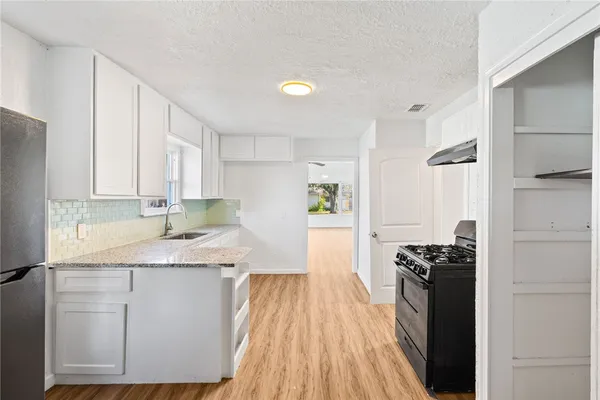 a kitchen with granite countertop a sink a stove and refrigerator