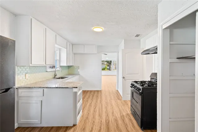 a kitchen with granite countertop a sink a stove and refrigerator