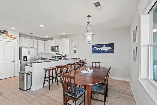 a view of a dining room and livingroom with furniture wooden floor a chandelier