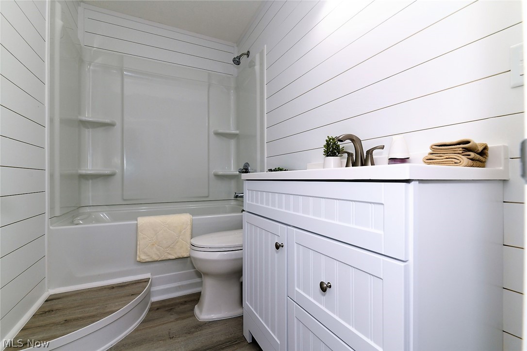 769 Patterson Avenue Akron, OH 44310 - Photo 19 of 27 *FULL BATHROOM REMODEL WITH SHIPLAPPED WALLS, STEP UP/DOWN CONVENIENT CORNER, NEW TUB AND SURROUND, FRESH WHITE VANITY WITH MOEN FAUCET AND TRIPLE SCONCE WALL LIGHTING ~