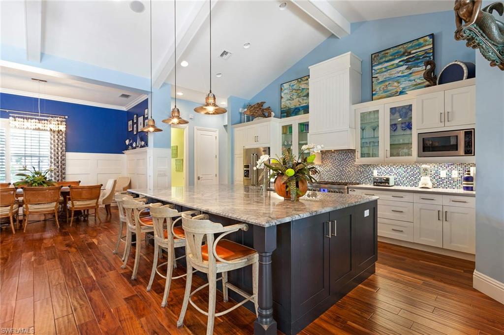 150 Central Avenue Naples, FL 34102 - Photo 6 of 35 a kitchen with stainless steel appliances kitchen island granite countertop a table chairs sink and cabinets