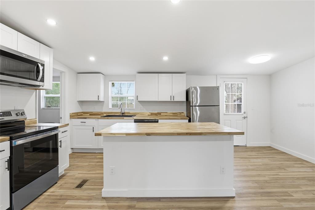 9024 Southwest 104th Terrace Gainesville, FL 32608 - Photo 14 of 21 a kitchen with stainless steel appliances granite countertop a stove top oven a sink dishwasher and a microwave oven with wooden floor