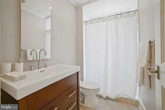 a bathroom with a sink a toilet a mirror and shower curtain