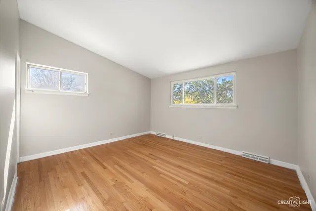 a view of empty room with wooden floor and fan