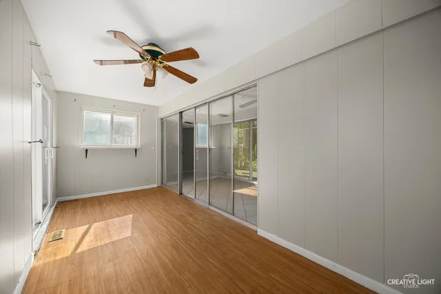 a view of empty room with wooden floor and fan