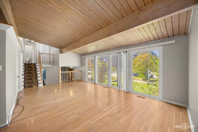 a view of an empty room with window and wooden floor