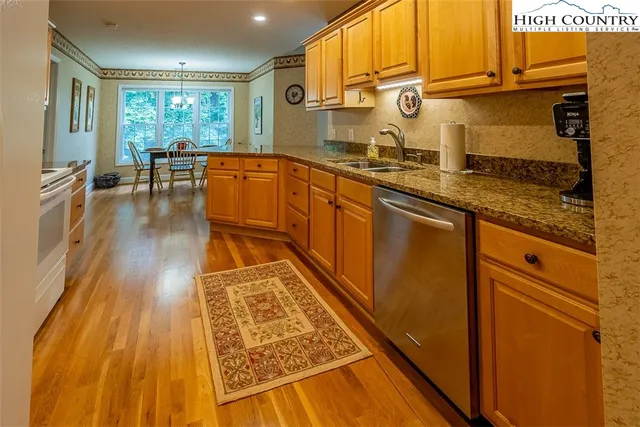 a kitchen with stainless steel appliances granite countertop a refrigerator a sink dishwasher and cabinets with wooden floor