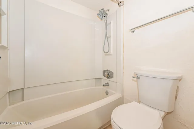a white toilet sitting next to a bath tub