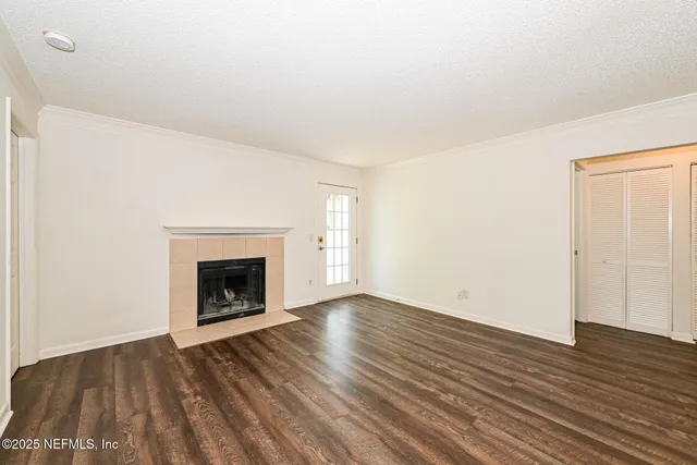 a view of an empty room with wooden floor fireplace and a window
