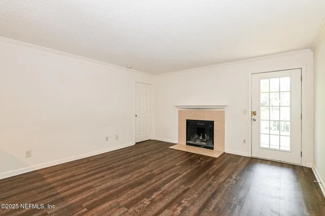 an empty room with wooden floor fireplace and windows