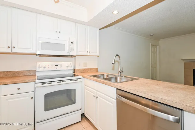 a kitchen with granite countertop white cabinets and white appliances