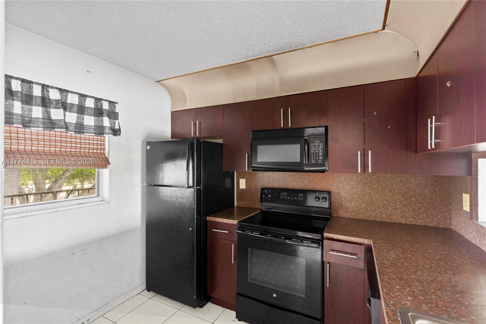 3199 Foxcroft Road, Unit 311 Miramar, FL 33025 - Photo 3 of 18 a kitchen with a refrigerator and a stove