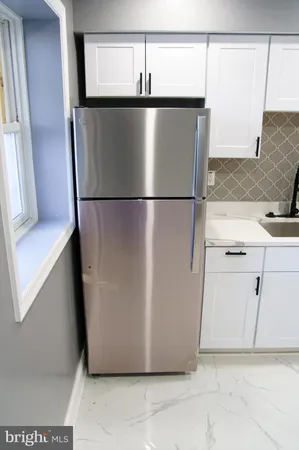 a view of a refrigerator in kitchen and an empty room