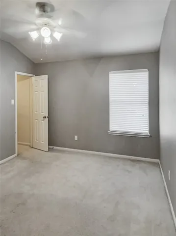 an empty room with a window and a chandelier fan