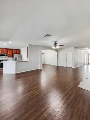 a view of a kitchen with wooden floor a ceiling fan and windows