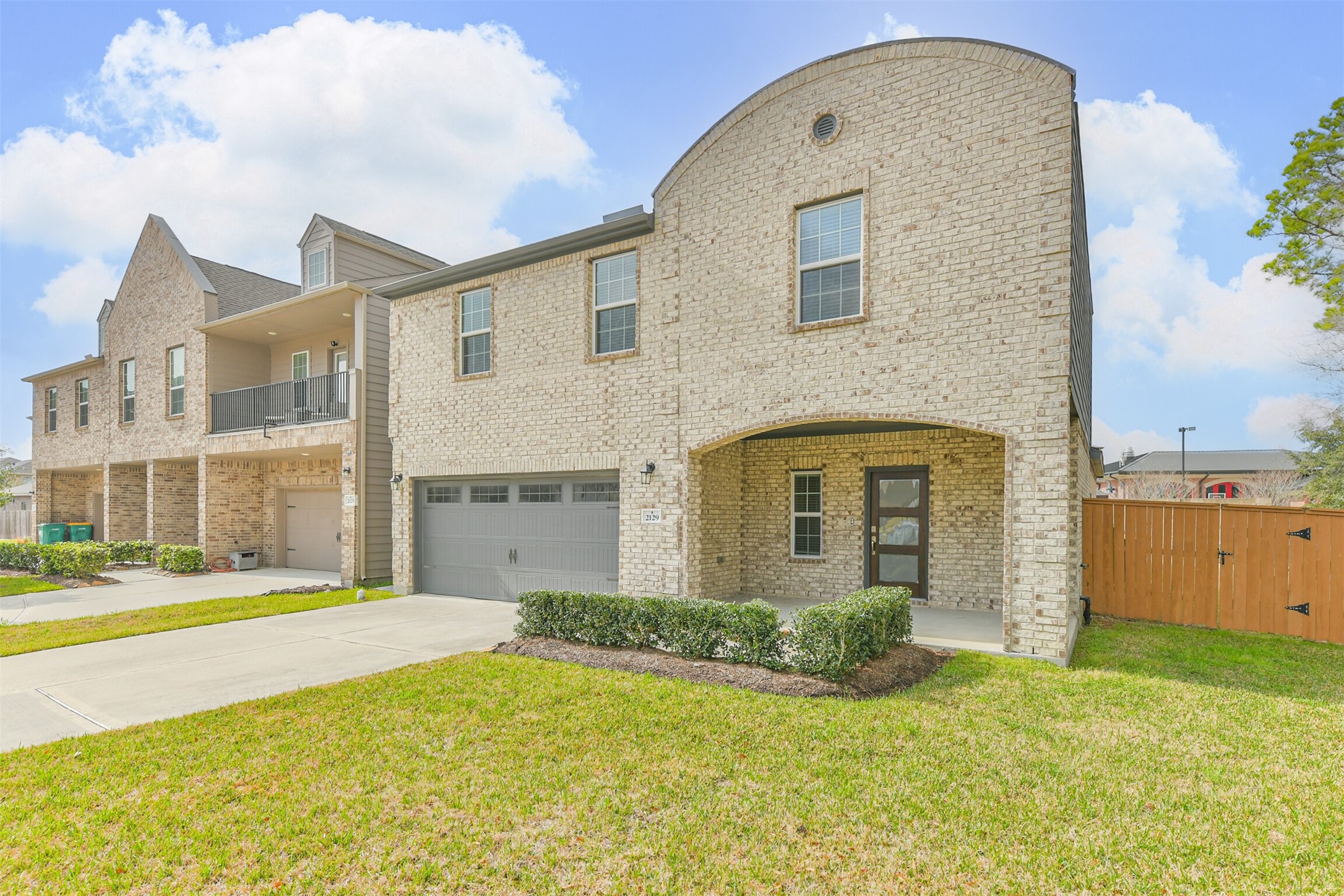 2129 Solstice Boulevard Spring, TX 77386 - Photo 2 of 49 Another great view of the brick exterior, showcasing the covered front porch and modern entry. Manicured landscaping, a wide driveway, and easy side-yard access through the privacy gate. Bright, open surroundings with well-kept neighboring homes.