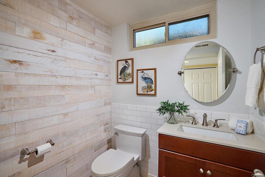 1323 Calle Scott Encinitas, CA 92024 - Photo 22 of 28 a bathroom with a granite countertop toilet sink mirror and vanity