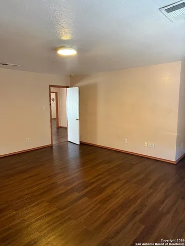 a view of an empty room with wooden floor