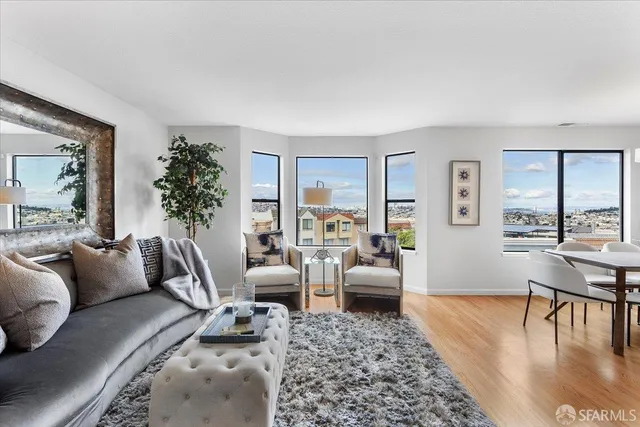 a living room with furniture large window and wooden floor