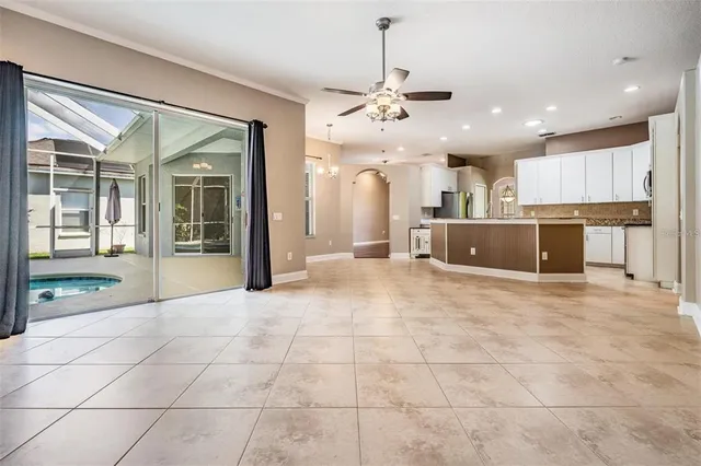 en empty room with windows and chandelier fan