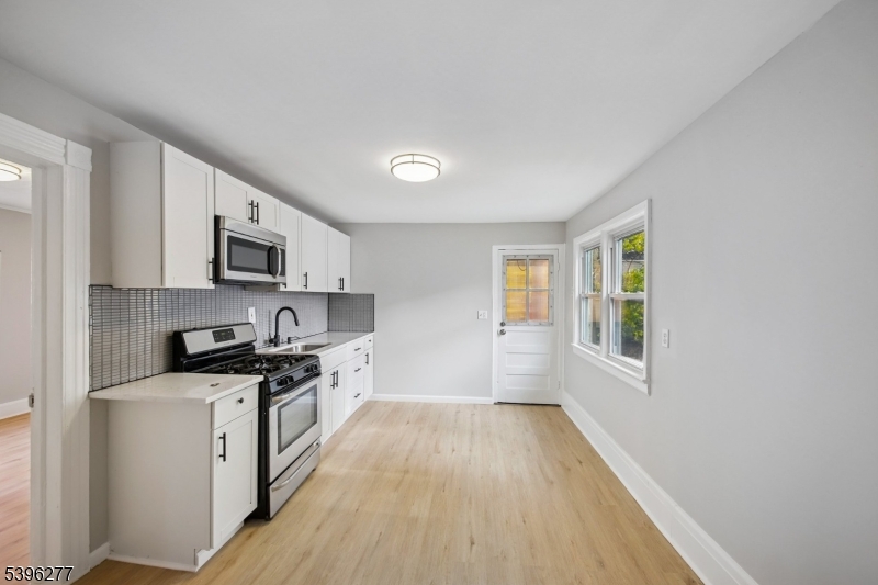 176 Valley Street, Unit 2 South Orange, NJ 07079 - Photo 6 of 30 a kitchen with stainless steel appliances a white stove top oven a sink dishwasher and a microwave with wooden floor