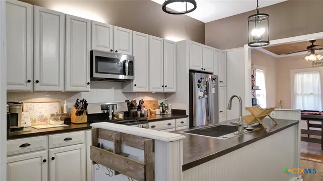 a kitchen with stainless steel appliances granite countertop a sink a stove and a refrigerator