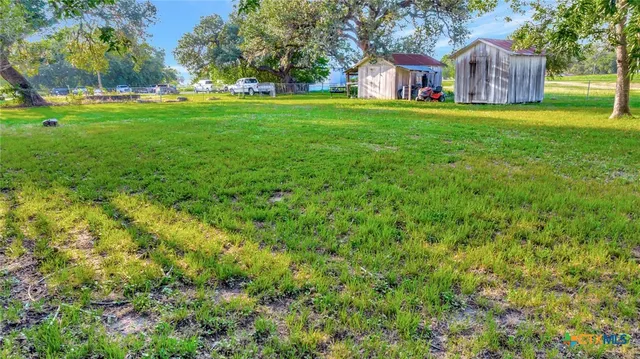 a view of a house with a big yard and large trees