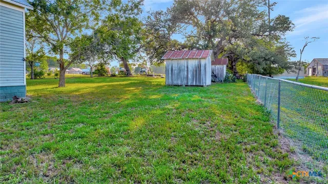 a view of a backyard with large trees and wooden fence