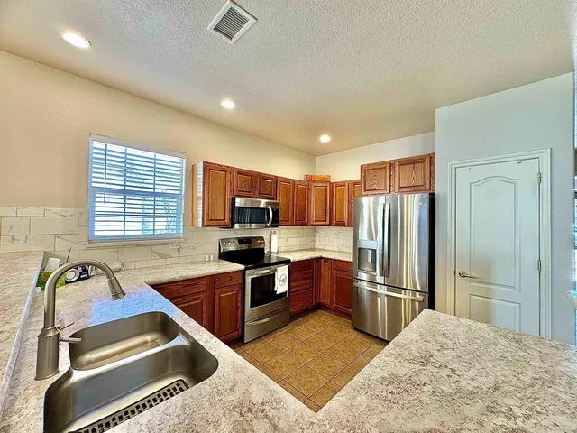 a kitchen with stainless steel appliances granite countertop a sink refrigerator and microwave
