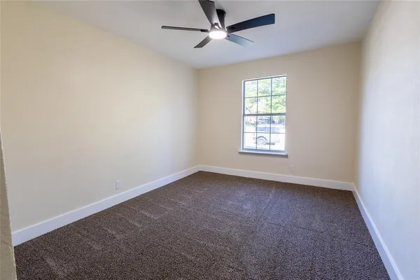an empty room with a window and a fan