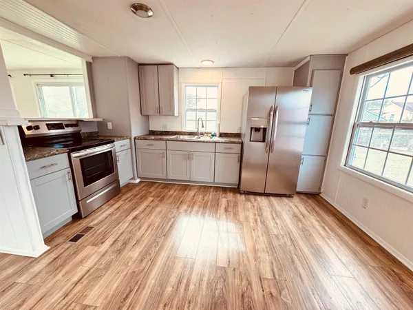a kitchen with granite countertop a refrigerator stove top oven and sink