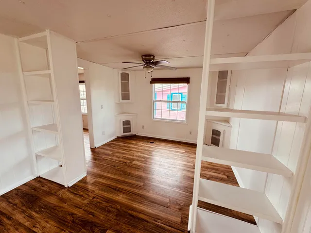 a view of a bedroom with wooden floor and windows