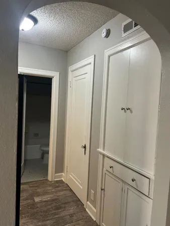 a view of a hallway with wooden floor and a bathroom