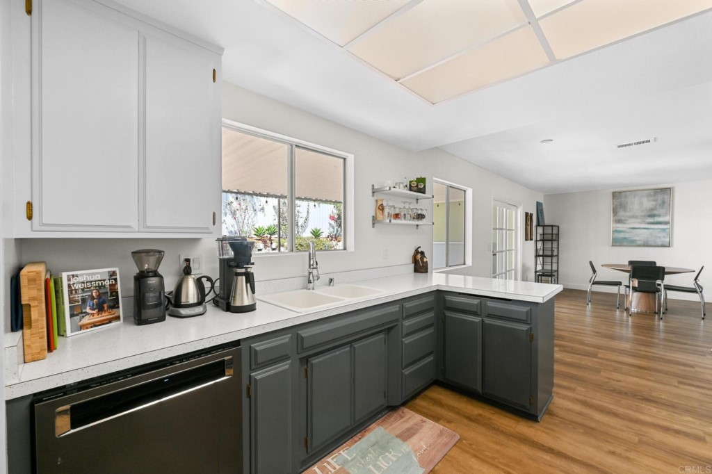 938 Doris Drive Encinitas, CA 92024 - Photo 12 of 31 a kitchen with stainless steel appliances granite countertop a sink dishwasher a stove and white cabinets with wooden floor