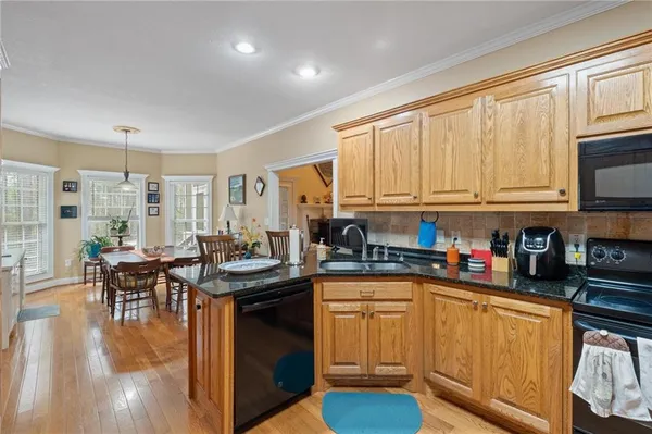 a kitchen with stainless steel appliances granite countertop a sink a stove top oven a chimney a counter space and a window