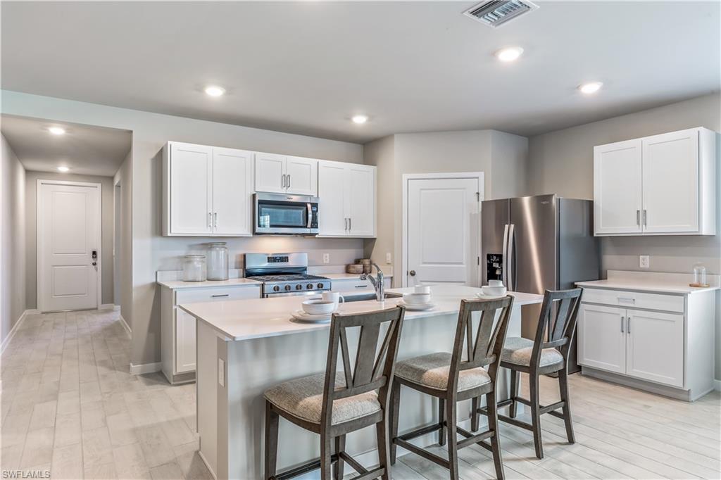 17770 Shade Tree Loop Punta Gorda, FL 33982 - Photo 5 of 47 a kitchen with refrigerator a stove a sink and chairs